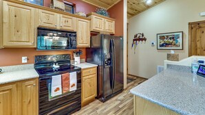 A kitchen with wooden cabinets, a stainless steel refrigerator, a microwave, and a stove. - Fireside Comfort & Family Fun: Wooded Show Low Gem (Show Low)