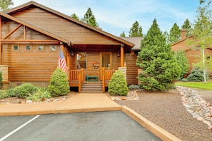 A wooden lodge with a porch, a flag, and a stone pathway leading to the entrance.