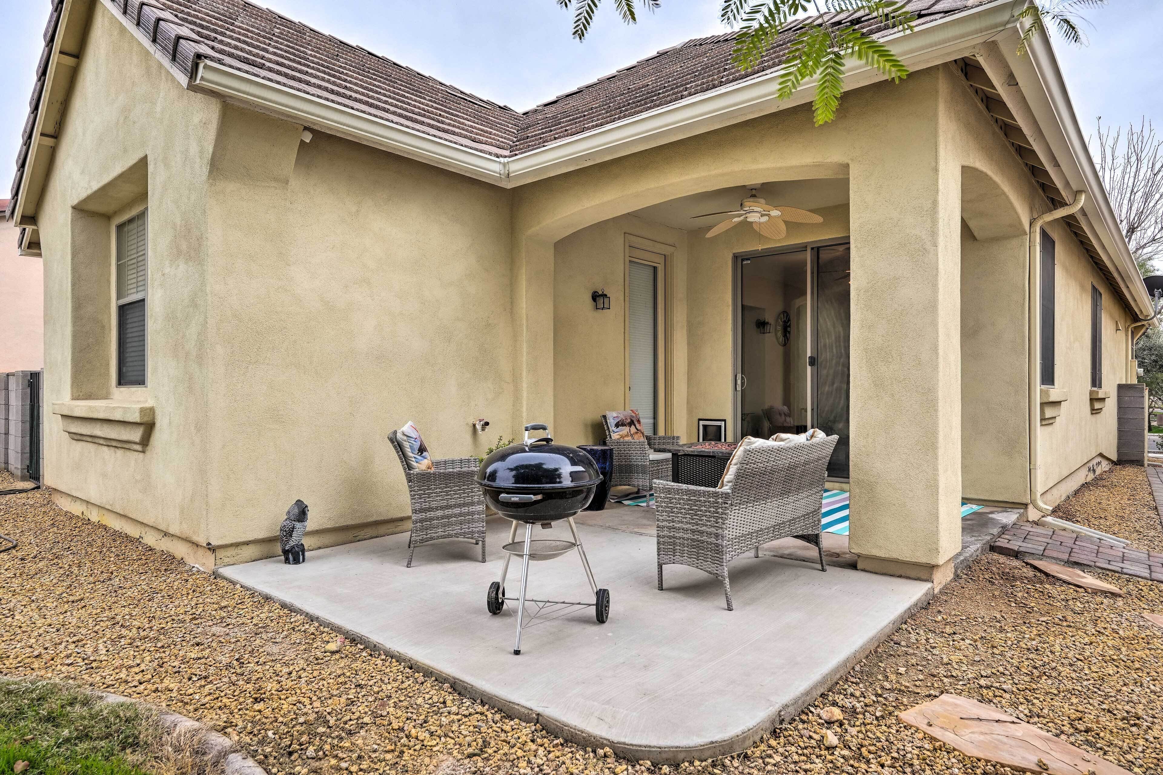A covered patio area with a grill, wicker furniture, and a door leading to an interior space.