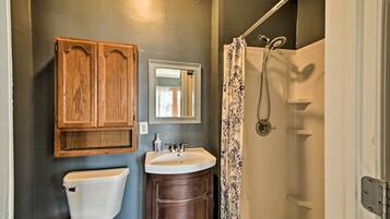 Une salle de bain avec un meuble en bois, un lavabo, des toilettes et une douche avec un rideau.