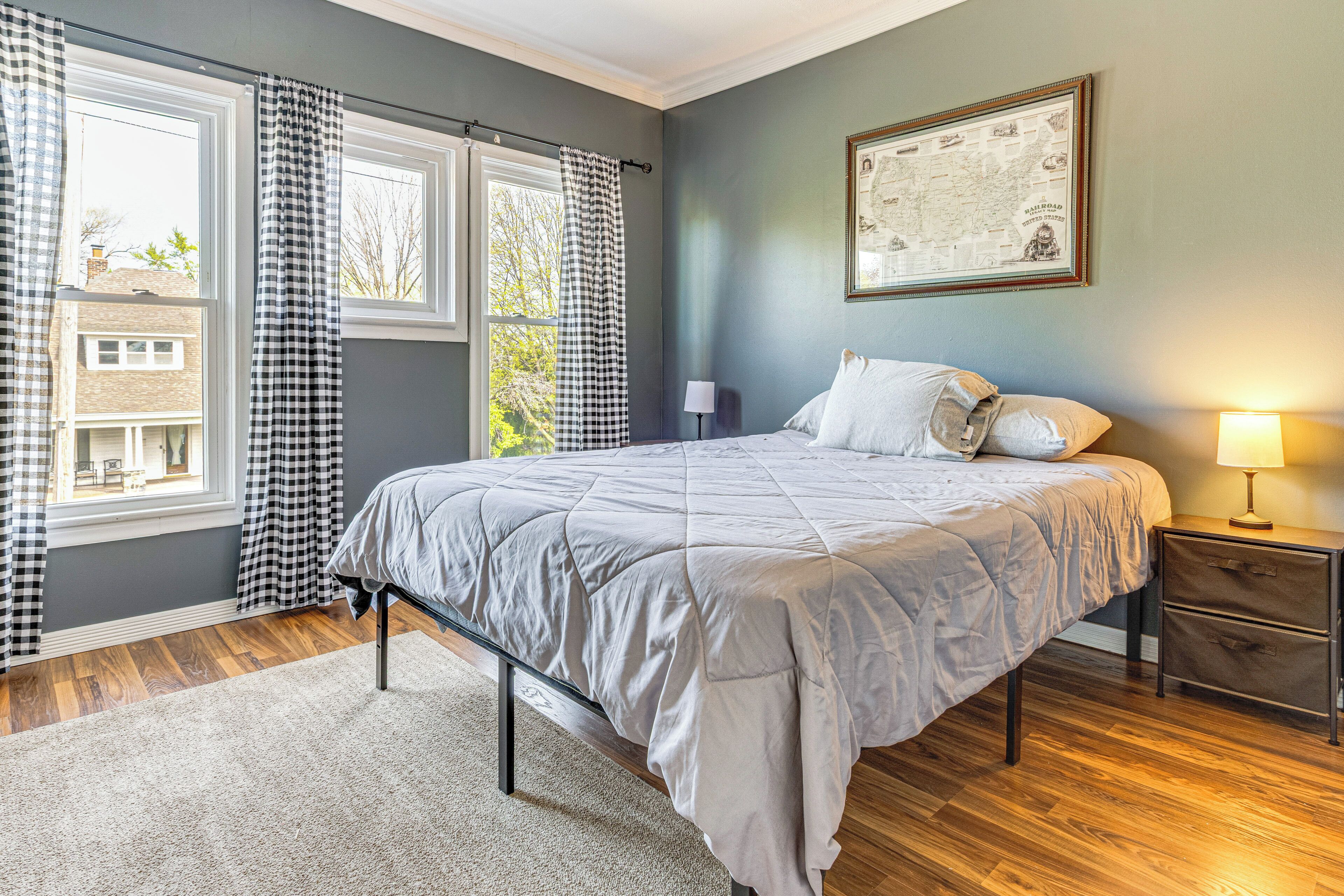 A bedroom with a bed, a nightstand, a lamp, and a window with curtains.