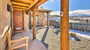 A wooden porch with a bench, a door, and a view of a snowy landscape. - Casita Vacation Rental Near Taos w/ Patio! (Taos)
