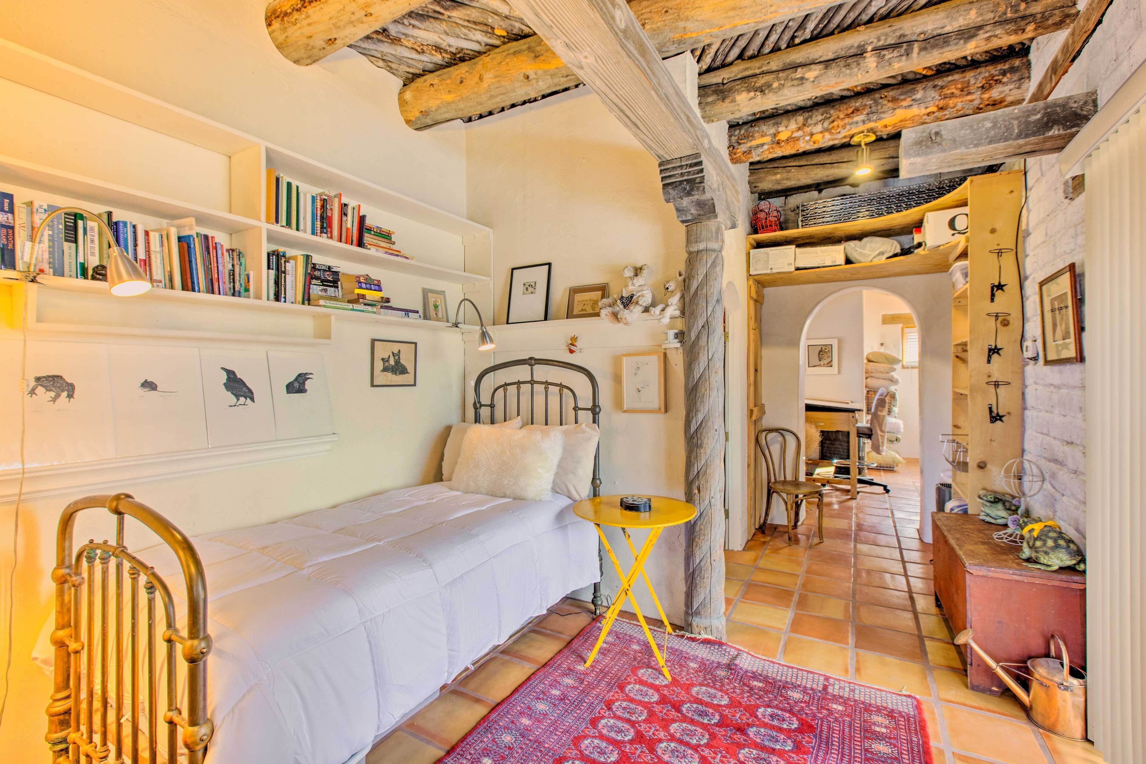 Een knus slaapkamer met een bed, een klein tafeltje en een boekenplank vol boeken.