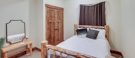 Ein Schlafzimmer mit einem hölzernen Bettgestell, einem Nachttisch, einem Spiegel und einem Kleiderschrank.