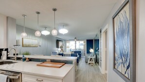 A modern kitchen with a central island, pendant lighting, and a dining area with a table and chairs. - Tranquil Redington Beach Condo w/ Beach Access (Redington Beach)