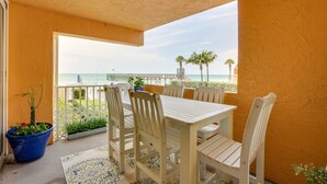 A balcony with a white table and chairs, a potted plant, and a view of the beach. - Tranquil Redington Beach Condo w/ Beach Access (Redington Beach)
