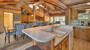 A spacious kitchen with a central island, wooden beams, and a dining area with grey upholstered chairs. - Ski & Soak: Hot Tub Haven in Tahoe City! (Tahoe City)