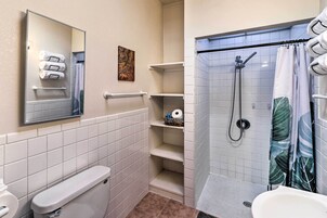 A bathroom with a toilet, a sink, a shower with a glass door, and a towel rack with towels.