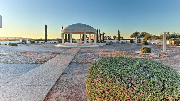 Un jardín paisajístico con senderos y setos recortados, y un pabellón.