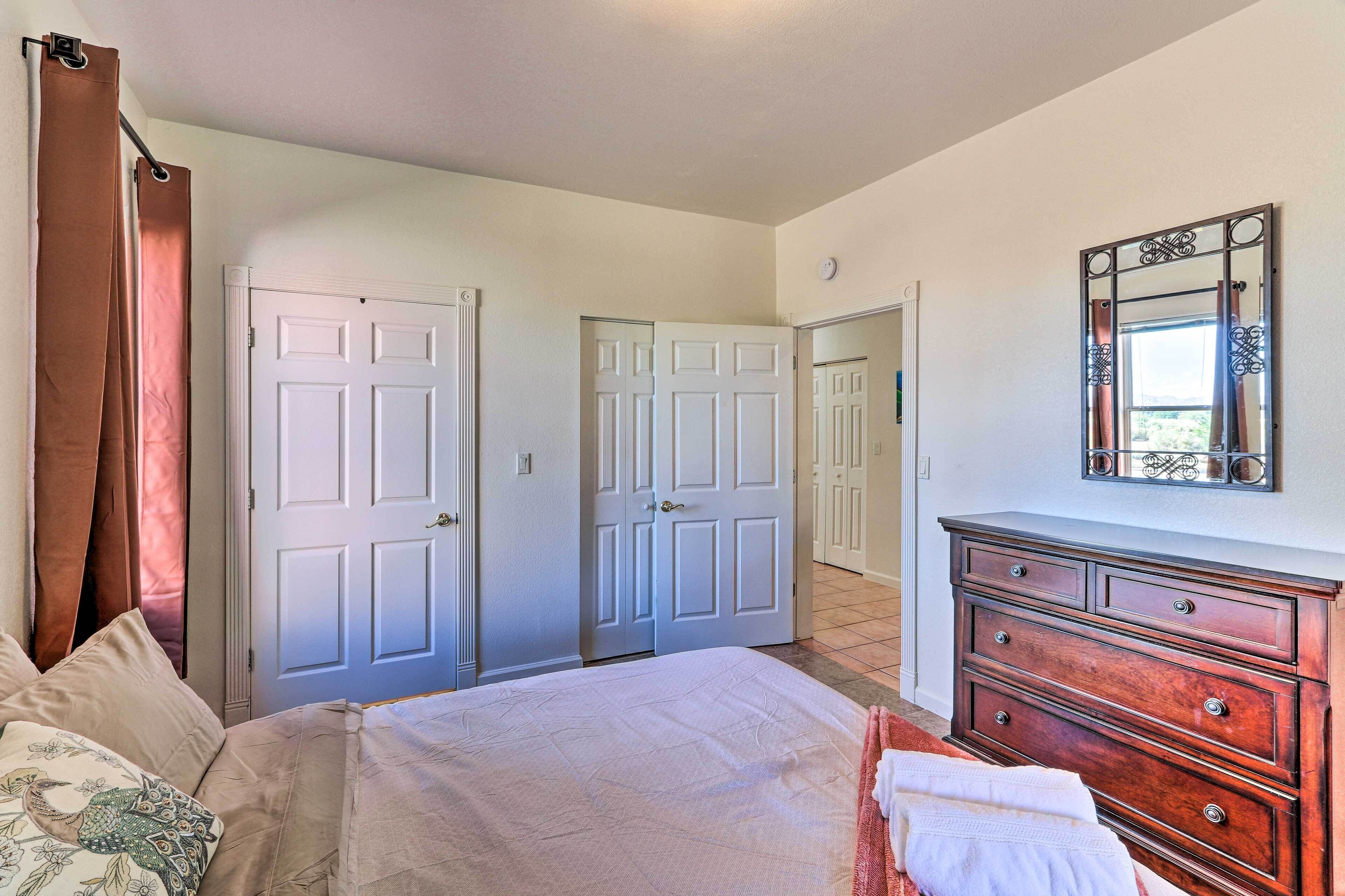 A bedroom with a bed, a dresser, and two doors leading to other rooms.