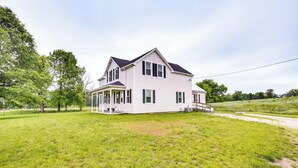 A two-story house with a porch, surrounded by a grassy yard and trees. - Peaceful Country Home in Serene Setting With Yard (Washington)
