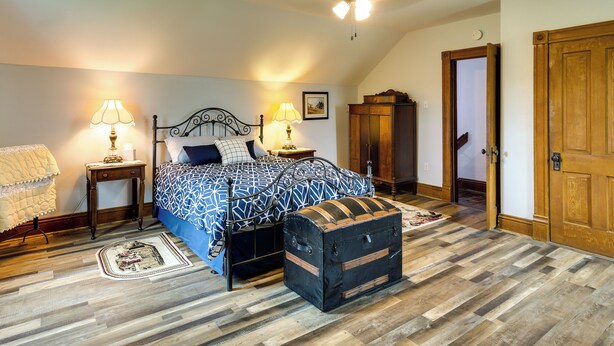 A bedroom with a bed, bedside lamps, a wooden chest, and a ceiling fan. - Peaceful Country Home in Serene Setting With Yard (Washington)