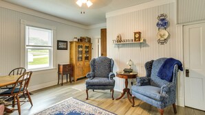 A room with a dining table, two armchairs, a wooden cabinet, and a blue rug. - Peaceful Country Home in Serene Setting With Yard (Washington)