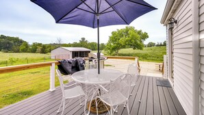 A wooden deck with a round table and chairs, a barbecue grill, and a large umbrella. - Peaceful Country Home in Serene Setting With Yard (Washington)