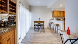 A modern kitchen with wooden cabinets, a central island with stools, and a red vase on the counter. - Comfortable Dallas Condo Close to Attractions (Dallas)