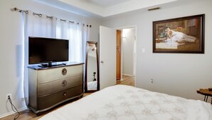 A bedroom with a bed, dresser, TV, and a painting on the wall. - Comfortable Dallas Condo Close to Attractions (Dallas)