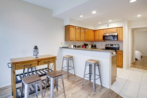 A kitchen with wooden cabinets, a stainless steel oven, and a bar area with stools. - Comfortable Dallas Condo Close to Attractions (Dallas)