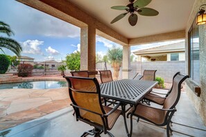 Un patio couvert avec une piscine, du mobilier d’extérieur et une vue sur les maisons voisines.