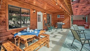 Uma cabana de madeira com área de jantar, com mesa posta, bancos e cadeiras.