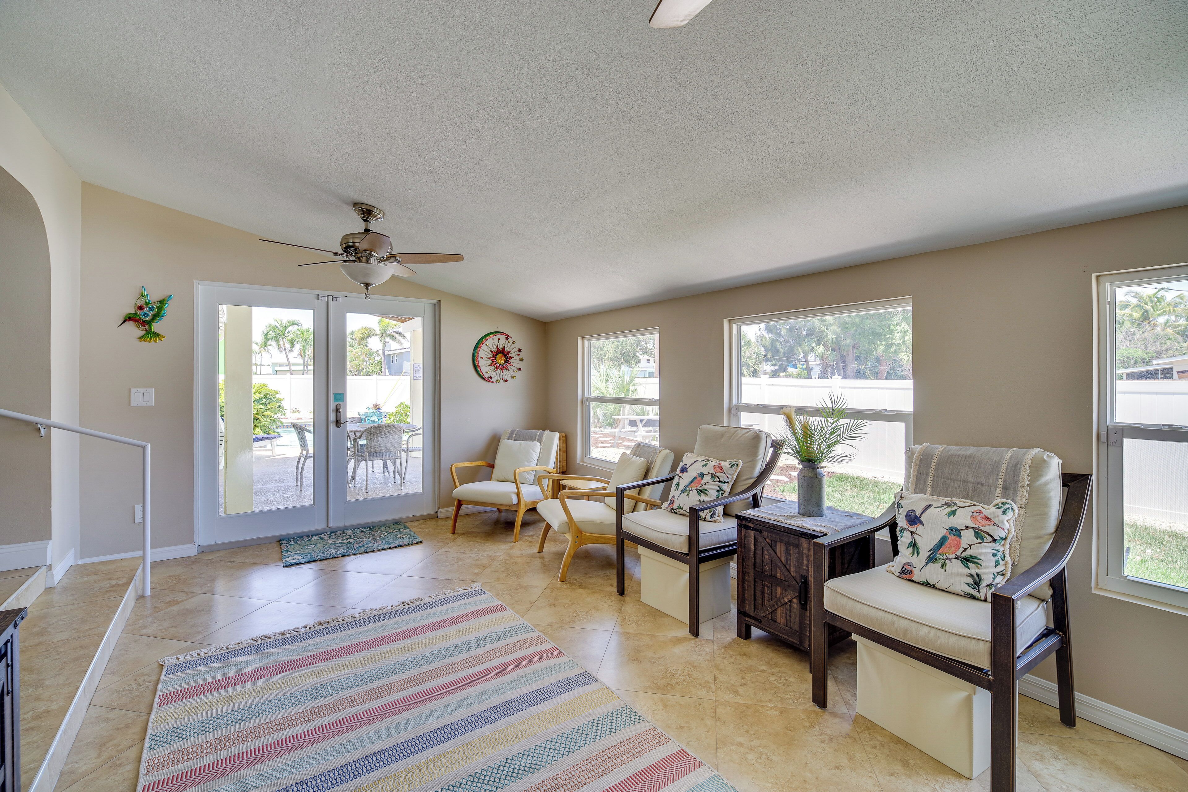 A spacious living area with a ceiling fan, a large window, and a door leading to an outdoor patio.