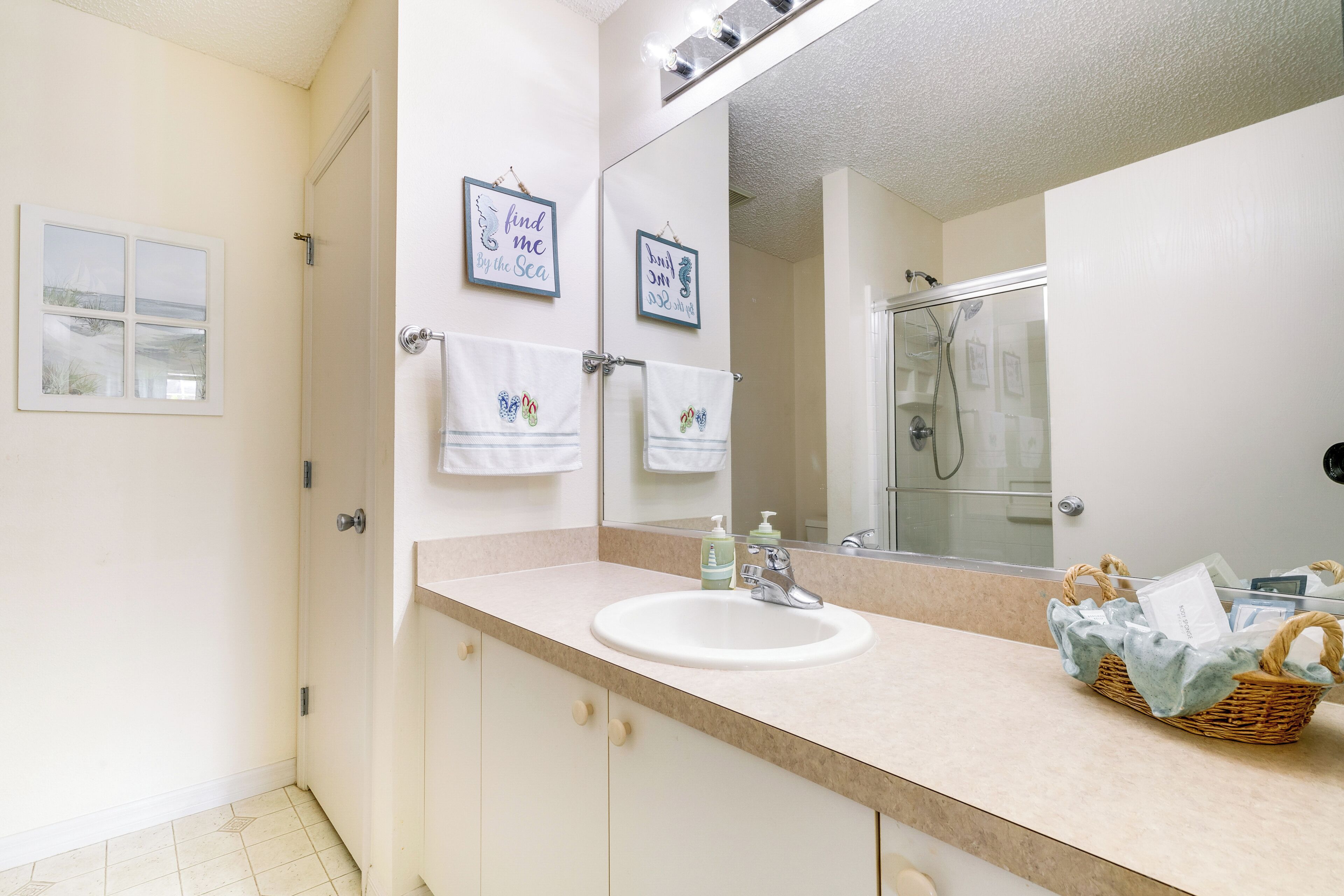 A bathroom with a white sink, a mirror, and two framed pictures on the wall.