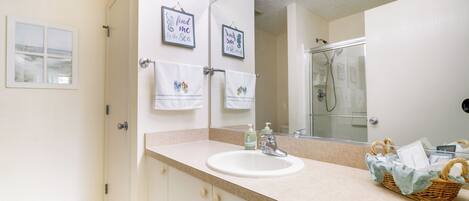 A bathroom with a white sink, a mirror, and two framed pictures on the wall.