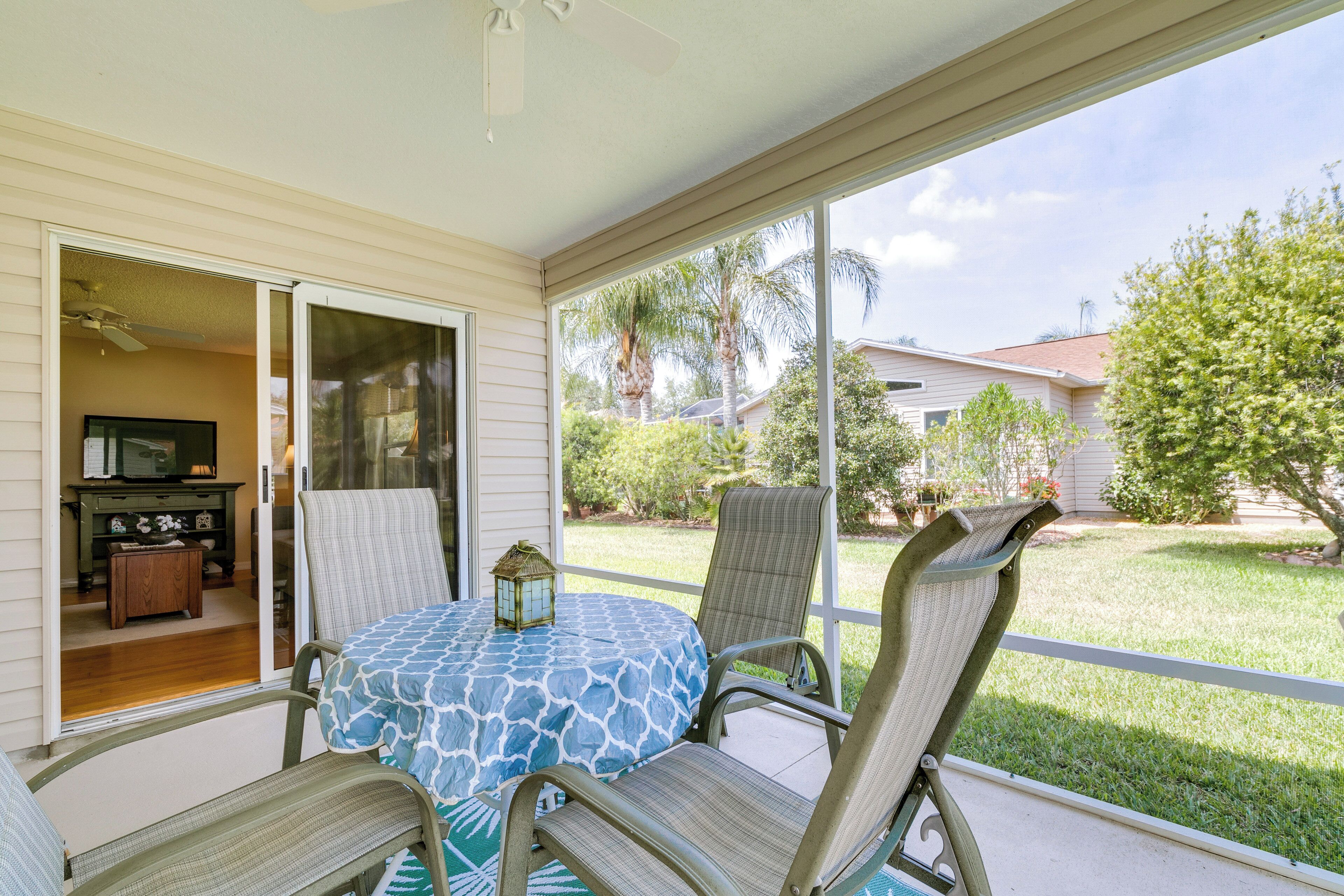 A covered patio with a table and chairs, a ceiling fan, and a view of the backyard.