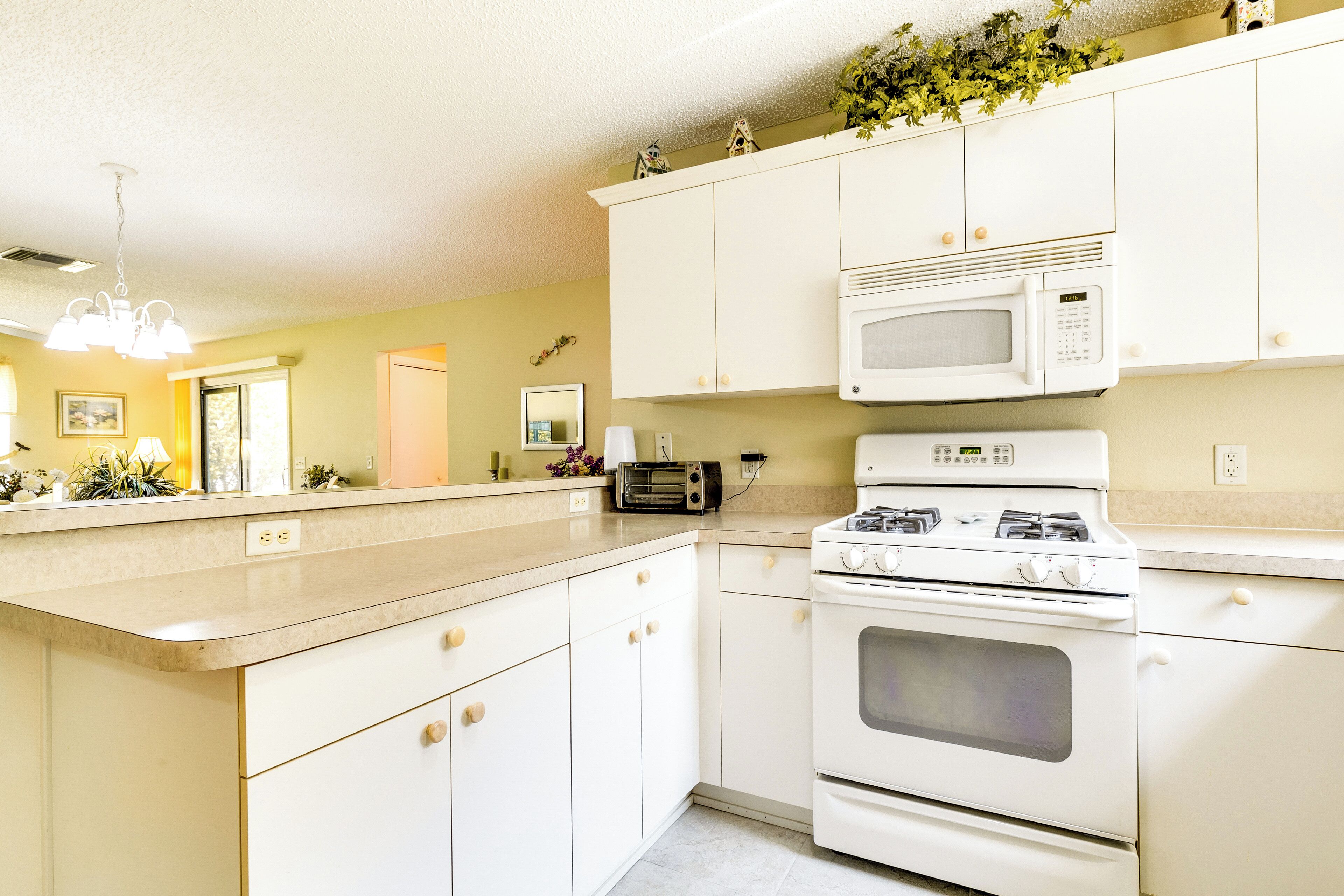 A kitchen with white cabinets, a microwave, a stove, and a toaster.
