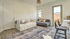 Un salon moderne avec un canapé blanc, un canapé gris, une table à manger avec des chaises et un tapis à motifs.