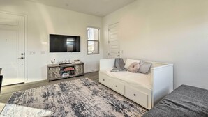 Un salon moderne avec un canapé blanc, un téléviseur à écran plat et un tapis à motifs.