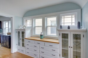 Una cocina con armarios blancos, encimera de madera y ventana con vistas.