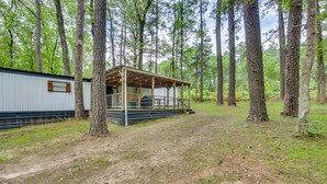A rustic cabin with a wooden deck and a covered porch, surrounded by tall trees in a wooded area. - Hemphill Home w/ Community Perks < 1 Mi to Water! (Hemphill)