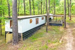 Une cabane dotée d’une véranda, entourée d’arbres.