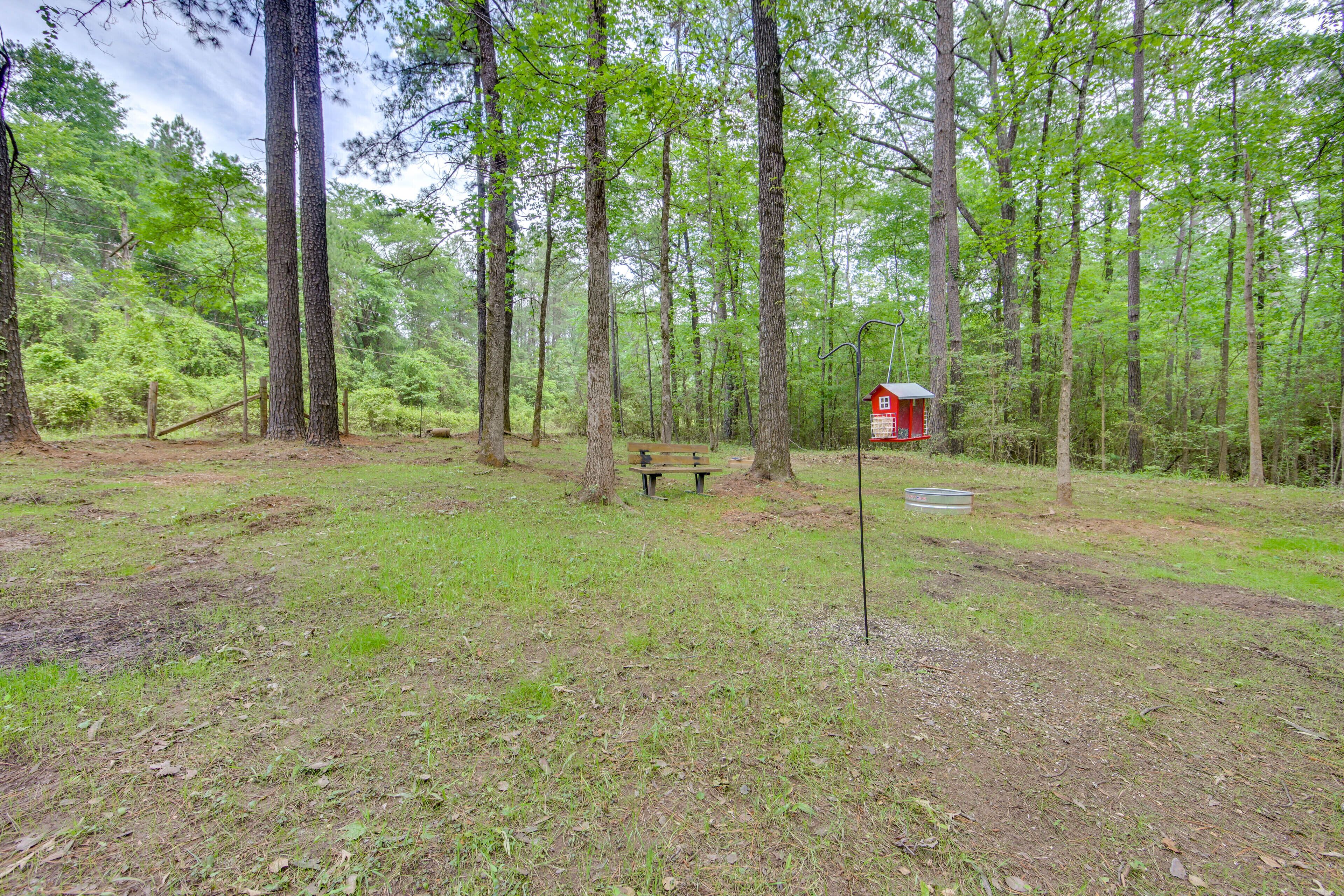 A forested area with a red cabin, a bench, and a metal sign.