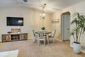 A dining area with a round table, chairs, a chandelier, a TV, and a sign that reads "Farmhouse." - Charming Anchorage Townhouse w/ Fire Pit! (Anchorage)
