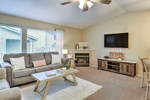 A living room with a sofa, coffee table, fireplace, TV, and a ceiling fan. - Charming Anchorage Townhouse w/ Fire Pit! (Anchorage)