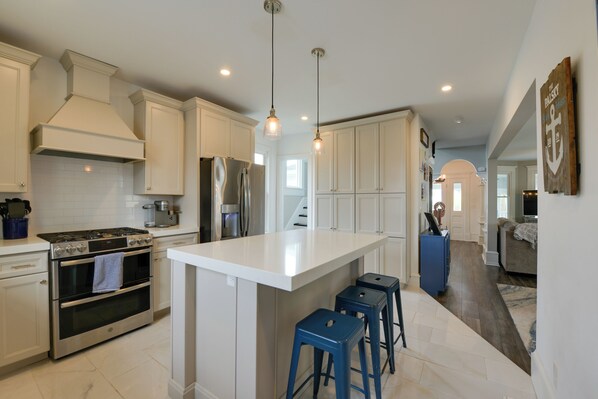 A modern kitchen with white cabinetry, stainless steel appliances, and a central island with bar stools.
