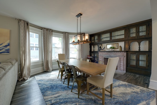 A dining room with a wooden table and chairs, a chandelier, and a fireplace.
