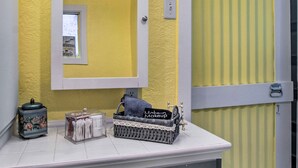 A bathroom with yellow walls, a white sink, a mirror, a tissue box, and a makeup basket. - Colorful Bisbee Home w/ Patio ~ 1 Mi to Dtwn! (Bisbee)