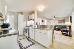 A modern kitchen with white cabinets, stainless steel appliances, and a dining area with a sofa and table. - Cozy Lewiston Home - Near Lakes & Restaurants! (Lewiston)