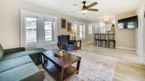 A spacious living room with a sofa, a coffee table, and a ceiling fan. There are large windows and a view of the outside. - Cozy Lewiston Home - Near Lakes & Restaurants! (Lewiston)