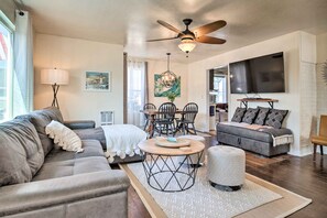 A modern living room with a sofa, ottoman, and a dining area with chairs and a table. - Charming Seaview Home w/ Bbq, Deck & Fire Pit (Seaview)