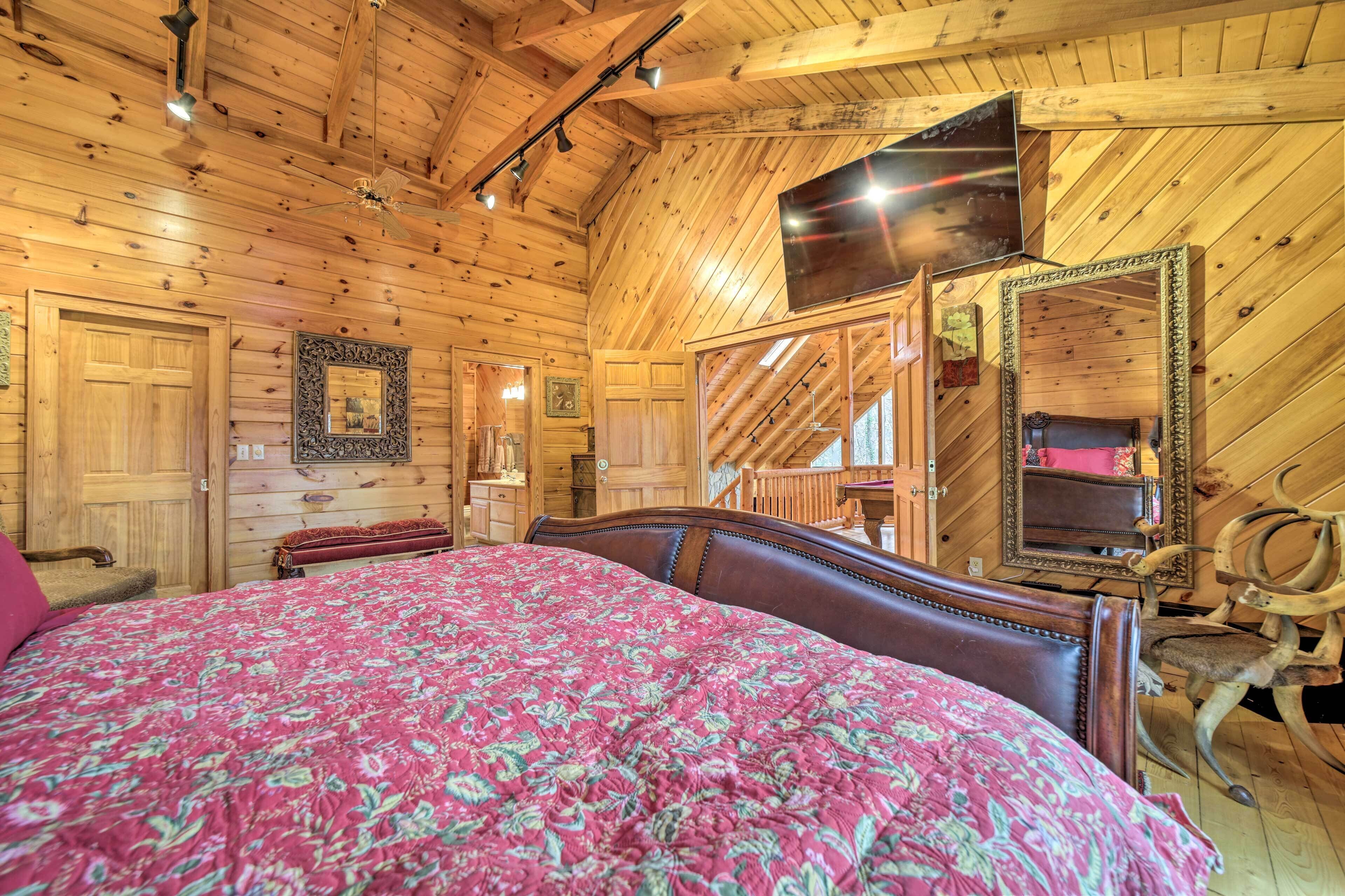 A wooden interior with a bed, a large mirror, and a ceiling fan.