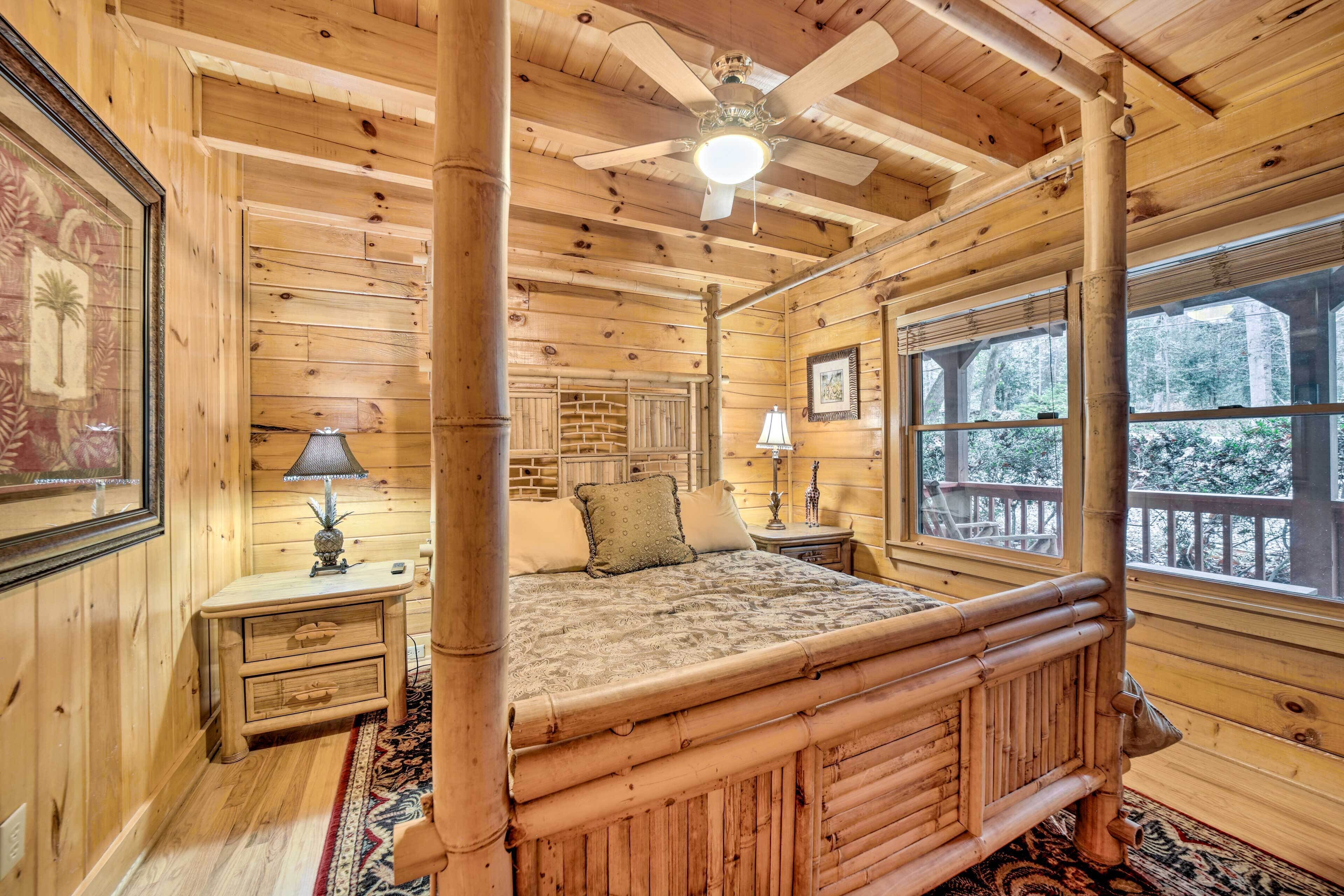 A wooden cabin bedroom with a four-poster bed, a ceiling fan, and large windows.