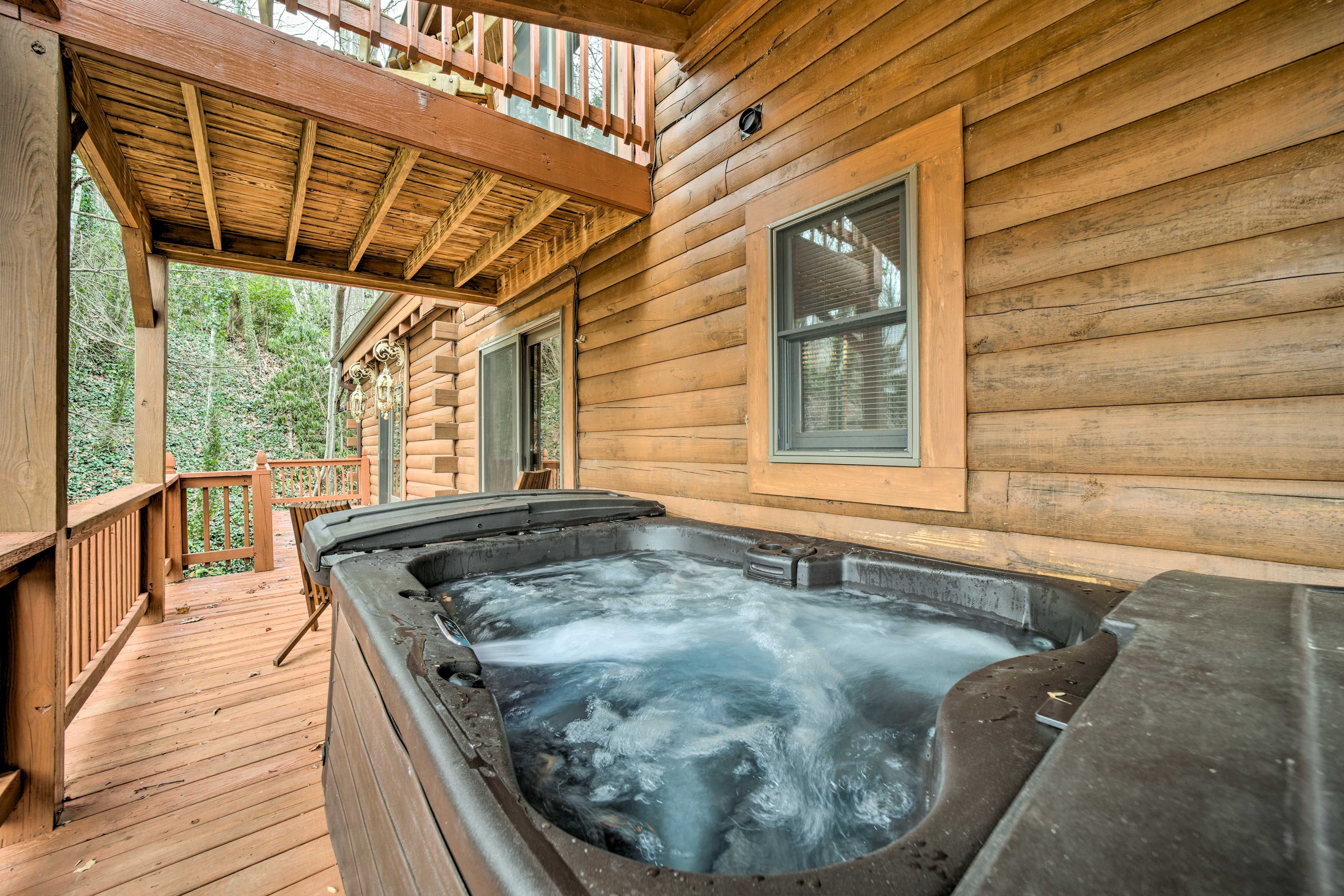 Eine Holzhütte mit Whirlpool auf einer Holzterrasse, umgeben von Bäumen.