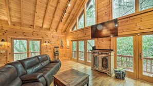 A spacious wooden cabin with a large leather sofa, a wooden coffee table, and a cabinet. - Walk to Golfing: Grand Maggie Valley Cabin! (Maggie Valley)
