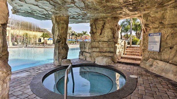 Ein mit Steinen umgebenes Whirlpool-Bereich mit einem Pool im Hintergrund.