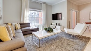 Ein modernes Wohnzimmer mit einer Couch, einem Couchtisch und einem weißen Sessel.