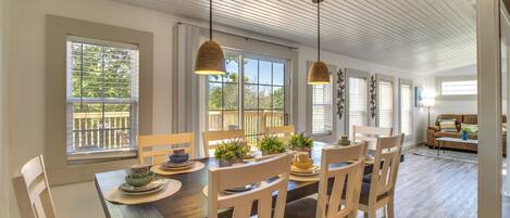 A dining area with a wooden table, chairs, and hanging pendant lights.