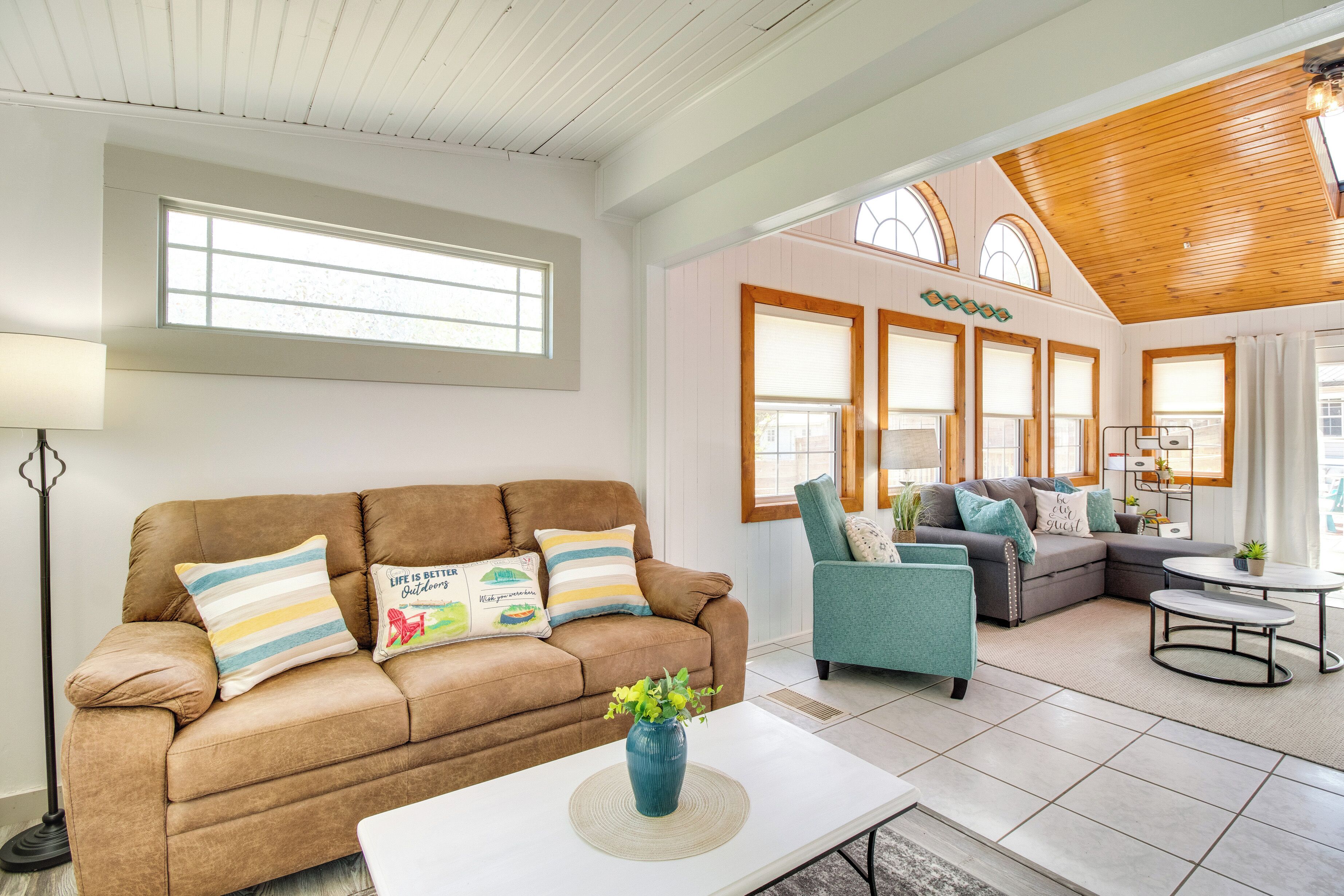A spacious living room with a brown sofa, teal armchair, and a coffee table.